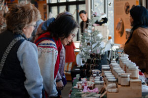 Several people look at jars of honey on a table 