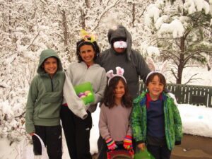 Person dressed in bunny suit poses with four children of various ages who are holding baskets 