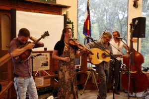 Four musicians indoors, playing upright bass, guitar, violin and mandolin