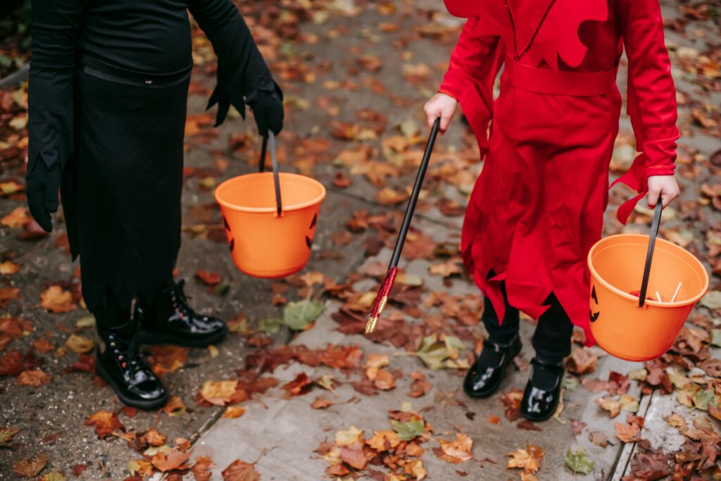 Two children trick or treating with pumpkin buckets