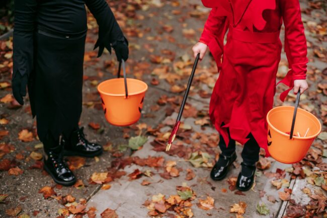 Two children trick or treating with pumpkin buckets