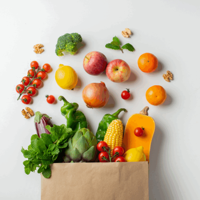 Healthy fruits and vegetables overflowing from a brown paper bag