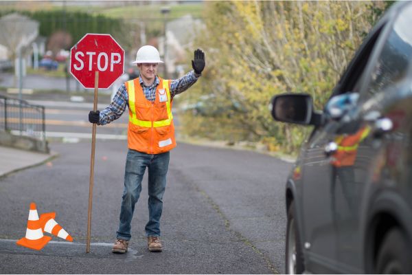Traffic man with a stop sign asking a car to stop.