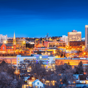 Downtown Colorado Springs at twilight with downtown buildings glowing on all the buildings