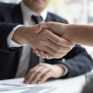 recruitment Person in suit and tie shaking hands with another individual