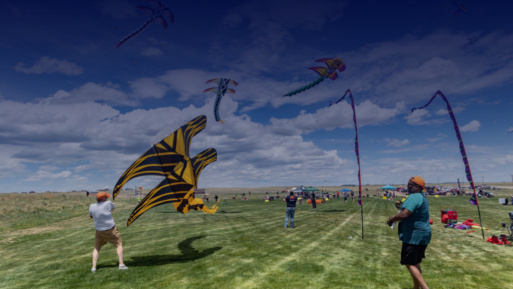 Several large colorful kites are being flown by El Paso County residents in an open El Paso County Park