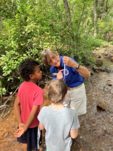 camp leader showing two young boys something from nature