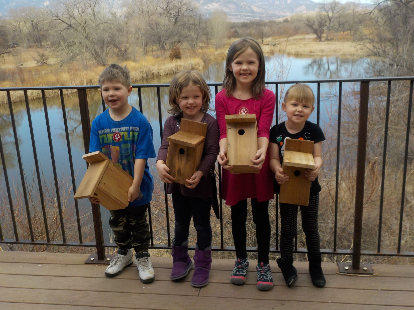 Children holding birdhouses they made on the deck of the nature center