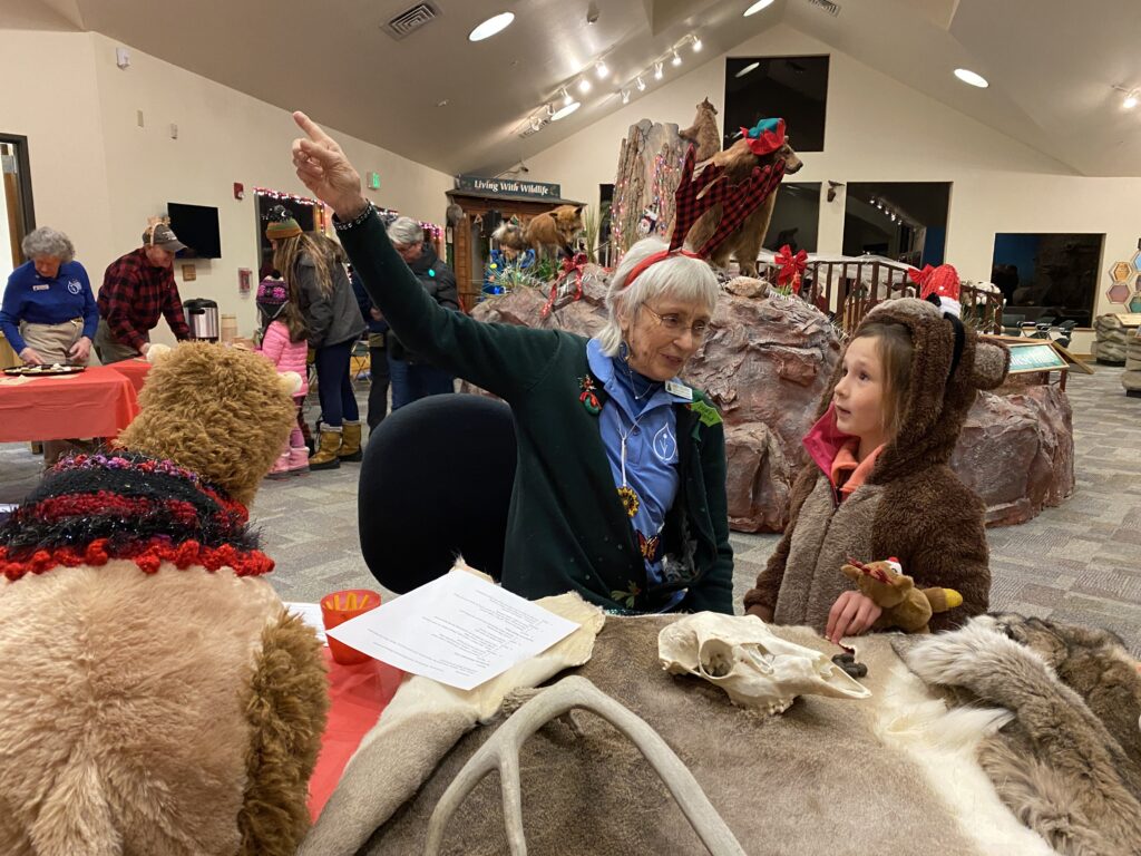 A woman points to an object while talking to a child in front of animal artifacts.