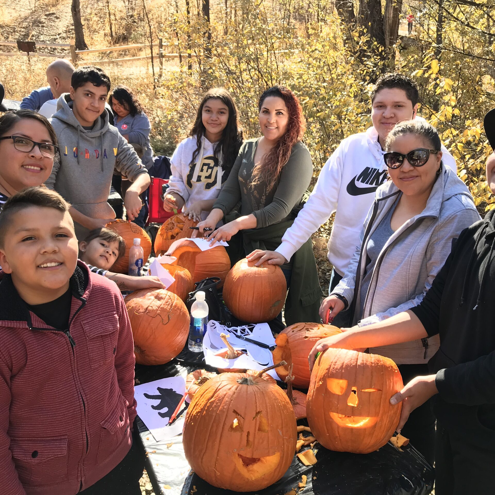 Pumpkin Carving Party A family smiles as they carve pumpkins into jack-o-lanterns outside on a fall day.
