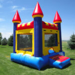 Bounce house on some grass with Pine trees in background